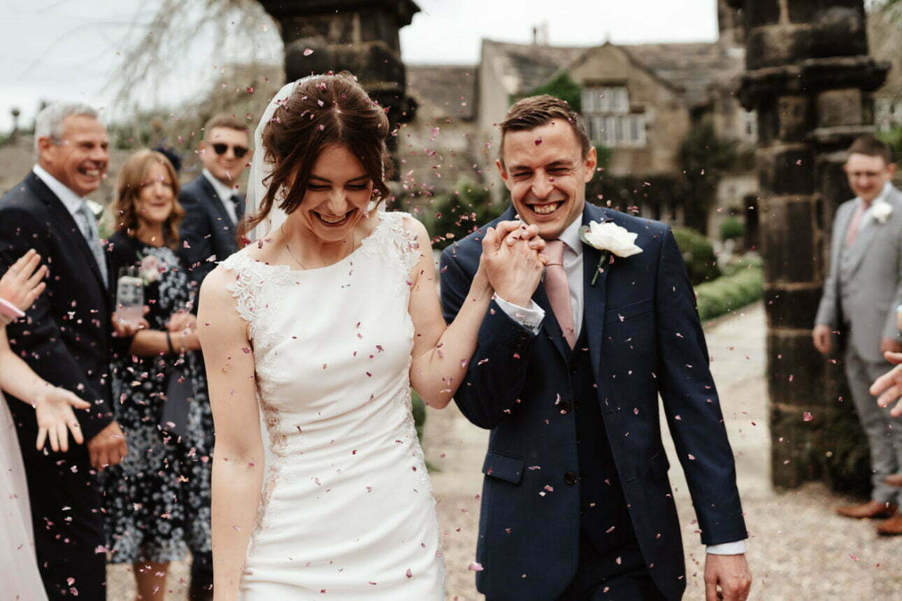 Confetti photography of bride and groom walking out of their venue
