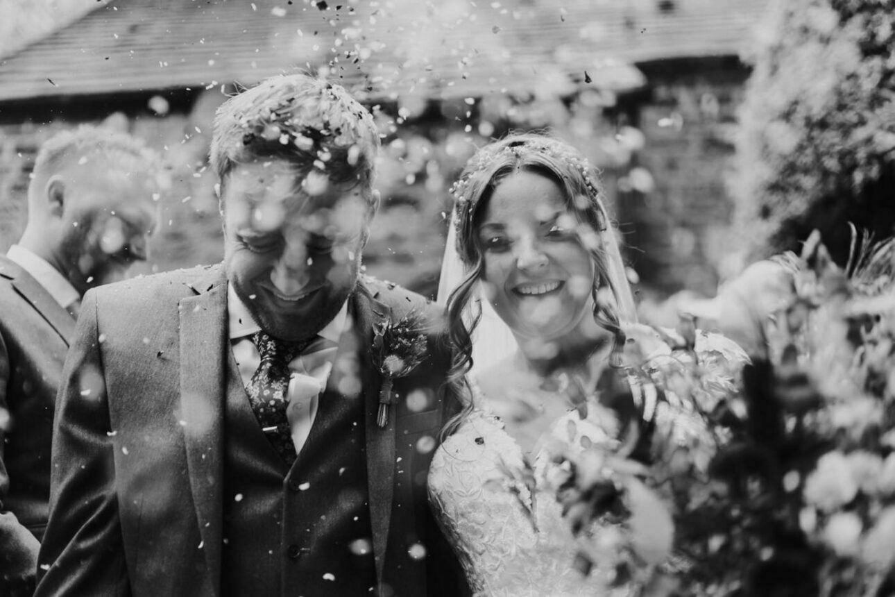 Confetti photography of bride and groom walking out of their venue

